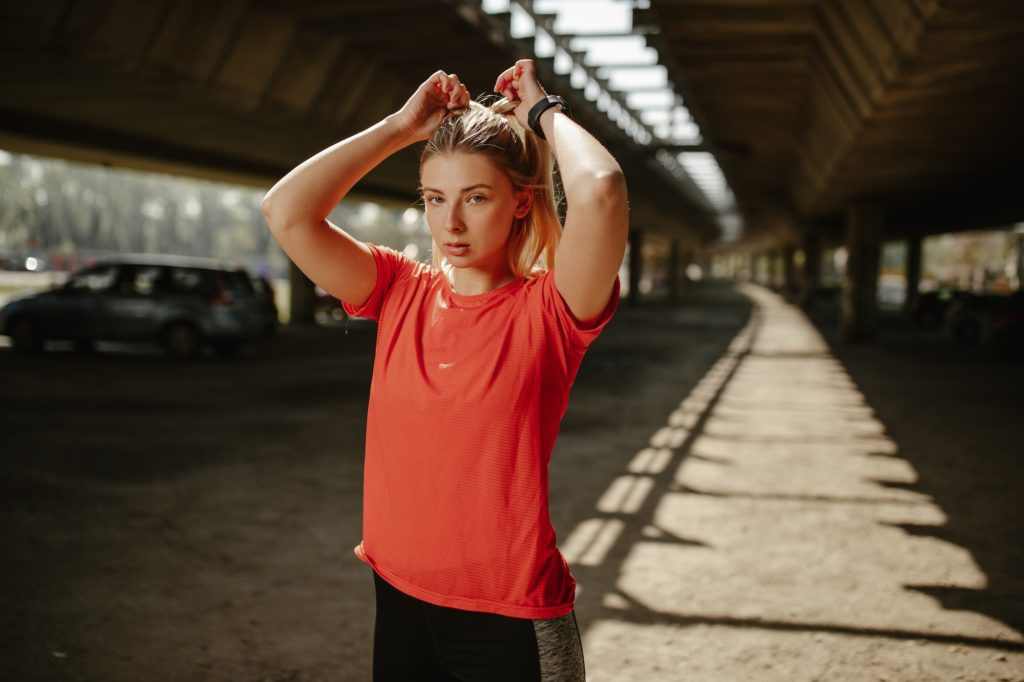 Athletic beautiful woman tying her hair. Sporty woman getting ready for workout.