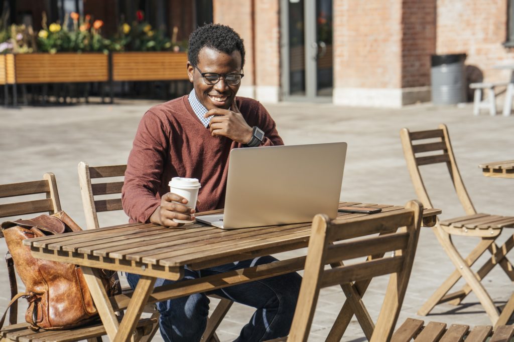 Young man using laptop in a coffee shop, drinking coffee